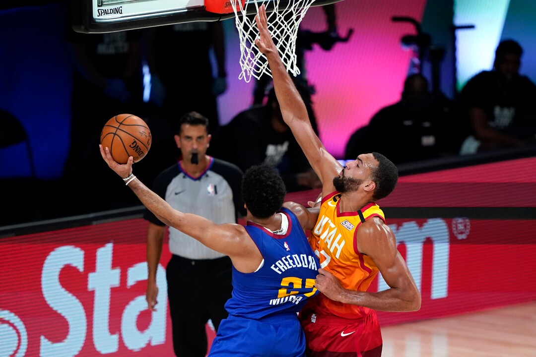 Utah Jazz's Rudy Gobert, right, grabs the jersey of Denver Nuggets' Jamal Murray as he shoots during the second half of an NBA basketball first round playoff game Sunday, Aug. 30, 2020, in Lake Buena Vista, Fla. (AP Photo/Ashley Landis)