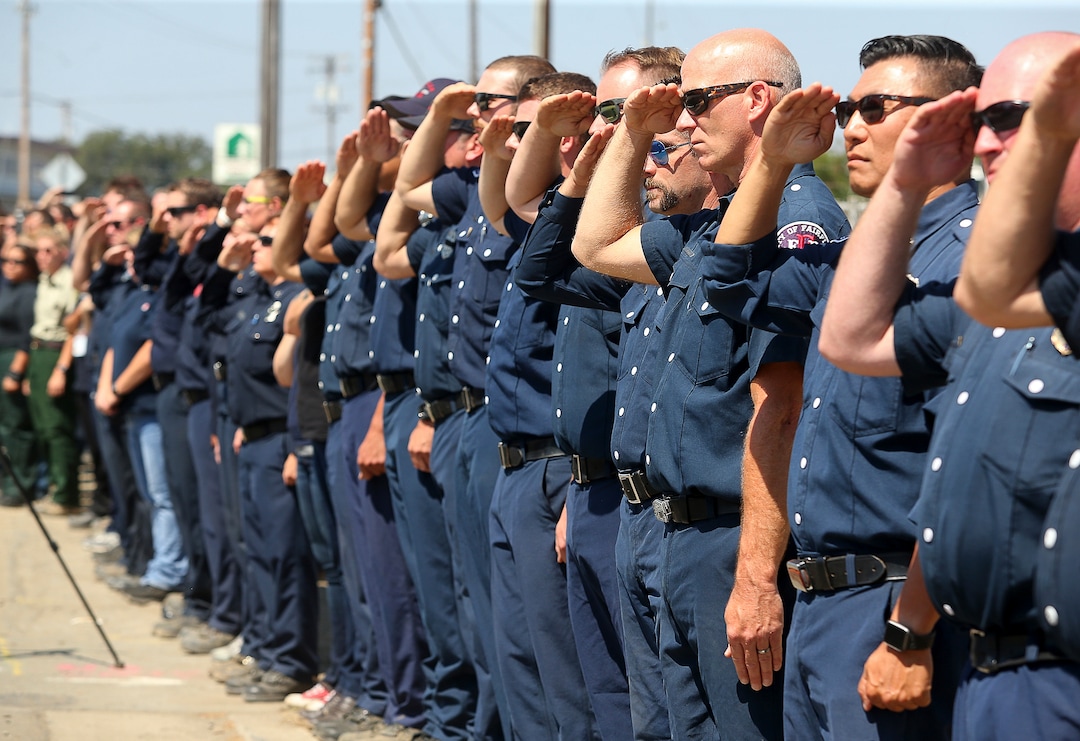 (Christopher Chung  |  The Press Democrat via AP)  Firefighting personnel from various agencies salute as the procession for Battalion Chief Matthew Burchett travels along North State Street, in Ukiah, Calif., on Wednesday, Aug. 15, 2018. Burchett said goodbye to his wife and 7-year-old son in early August, volunteering to travel with fellow firefighters from Utah to help battle record-setting blazes in California. Burchett was hit by a falling tree and died Monday night while fighting the largest blaze in California history, the Mendocino Complex fire north of San Francisco.
