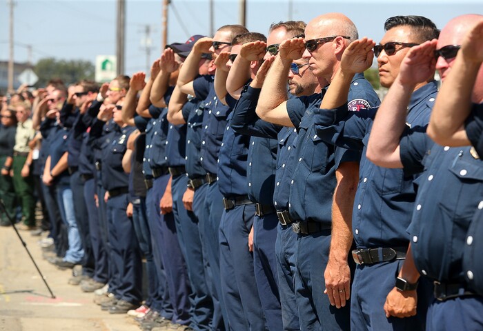 (Christopher Chung  |  The Press Democrat via AP)  Firefighting personnel from various agencies salute as the procession for Battalion Chief Matthew Burchett travels along North State Street, in Ukiah, Calif., on Wednesday, Aug. 15, 2018. Burchett said goodbye to his wife and 7-year-old son in early August, volunteering to travel with fellow firefighters from Utah to help battle record-setting blazes in California. Burchett was hit by a falling tree and died Monday night while fighting the largest blaze in California history, the Mendocino Complex fire north of San Francisco.
