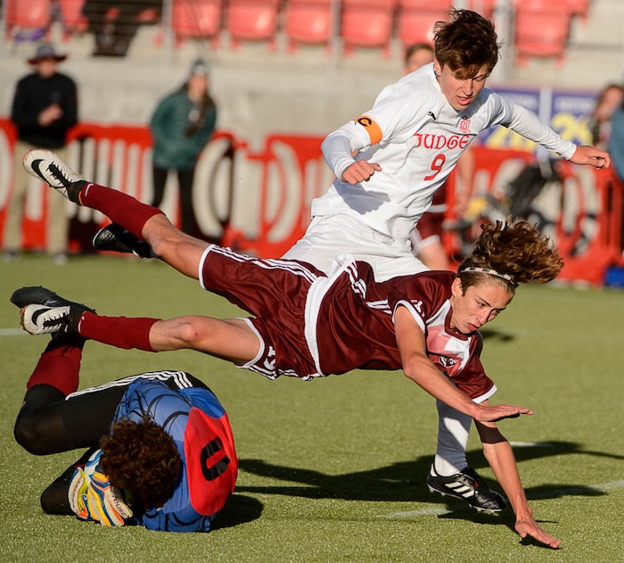 (Trent Nelson | The Salt Lake Tribune)  Morgan's Jaden Mellott leaps over his goalkeeper Trek Loveridge while facing Judge Memorial High School in the 3A state championship game, Saturday May 12, 2018. Judge's Jack Terrill at rear.