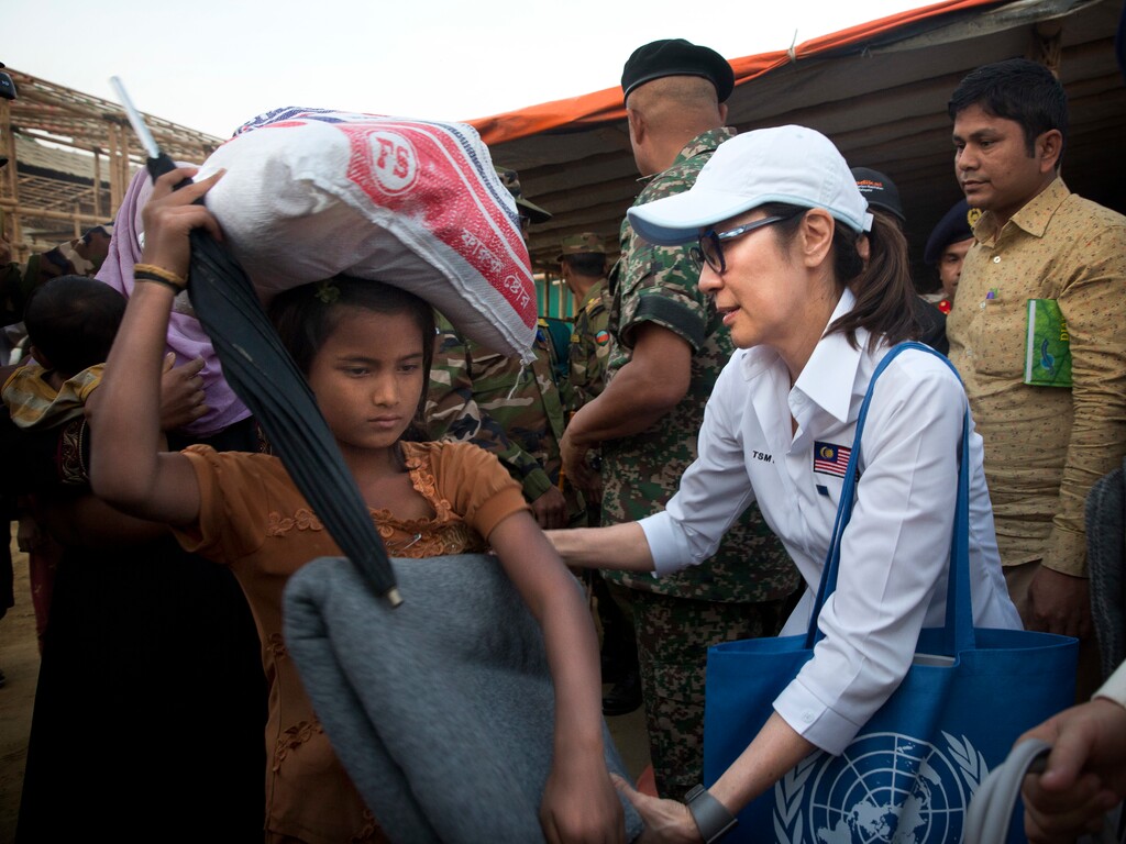 Malaysian actress Michelle Yeoh, right, distributes blanket to a Rohingya refugee at Balukhali refugee camp near Cox's Bazar, Bangladesh, Saturday, Jan. 27, 2018. A special delegation led by Michelle Yeoh and Malaysian Armed Forces Chief Gen. Raja Mohamad Affandi Saturday visited Rohingya refugee camp and distributed relief material items apart from evaluating the impact of the aid. (AP Photo/Manish Swarup)