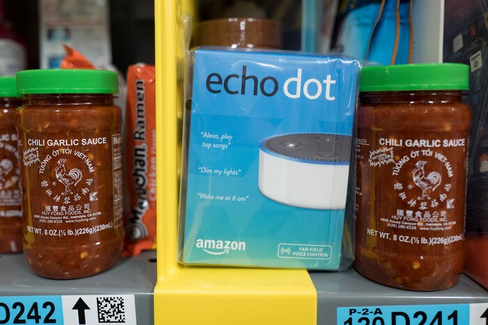 In this Wednesday, Dec. 20, 2017, photo, the Amazon Echo Dot is stocked on a shelf alongside jars of Garlic Chili Sauce at the Amazon Prime warehouse in New York. (AP Photo/Mark Lennihan)