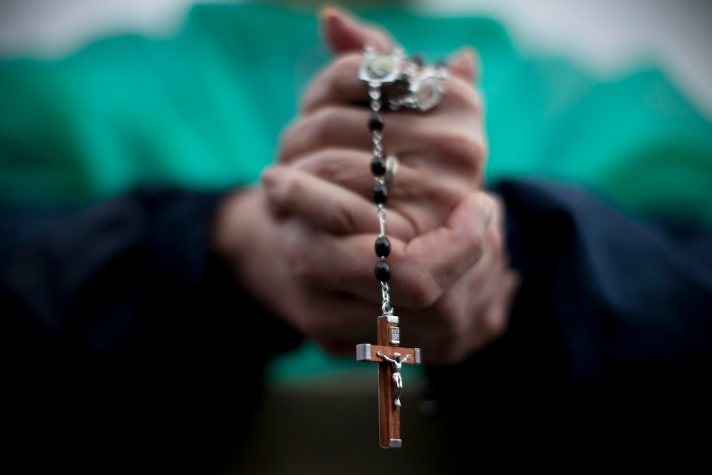 A woman holds a cross as she waits in St. Peter's Square on the second day of the conclave to elect a new pope, at the Vatican, Wednesday, March 13, 2013. Black smoke again billowed from the chimney of the Sistine Chapel on Wednesday, meaning that Catholic cardinals hadn't elected a pope on their second or third rounds of balloting. (AP Photo/Oded Balilty)