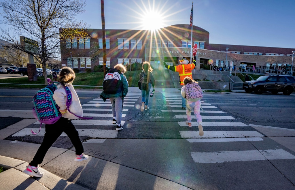 (Francisco Kjolseth  | The Salt Lake Tribune) A local crossing guard helps students cross the street on Tuesday, April 20, 2021.