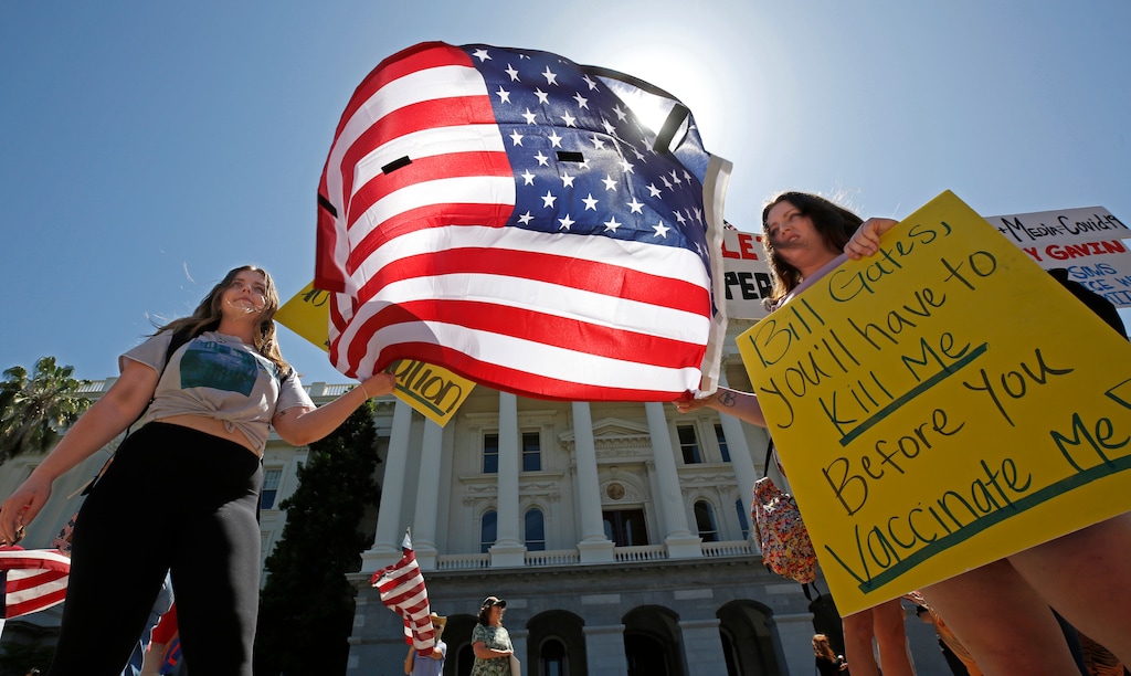 (Rich Pedroncelli | AP) Rachael Rathjen, left, and her sister, Alex, right, traveled from Riverside to join other protesters calling for the end of Gov. Gavin Newsom's stay-at-home orders at the state Capitol in Sacramento, Calif., May 1, 2020. Hundreds gathered calling for Newsom to ease the restrictions and allow people return to work.