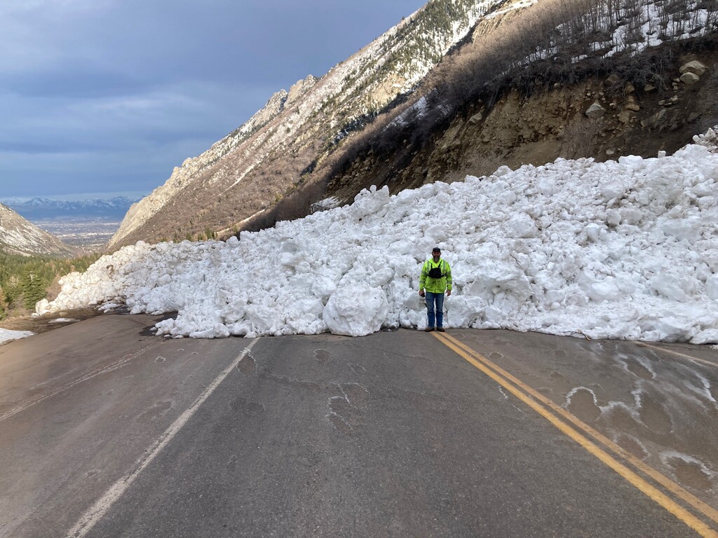 (Utah Department of Transportation) A UDOT worker stands in front of a slide in the Seven Turns avalanche path that crossed State Route 210 through Little Cottonwood Canyon on April 13, 2023. The agency had to close the canyon completely for eight days in an 11-day stretch at the beginning of April 2023 because of high avalanche danger.