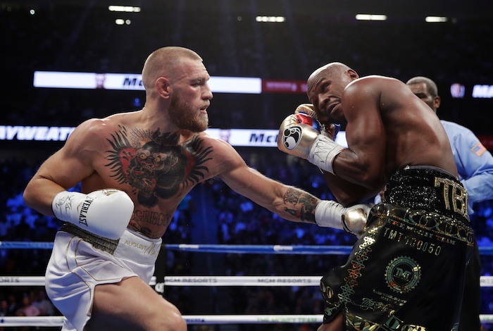 Conor McGregor, left, fights Floyd Mayweather Jr. in a super welterweight boxing match Saturday, Aug. 26, 2017, in Las Vegas. (AP Photo/Isaac Brekken)