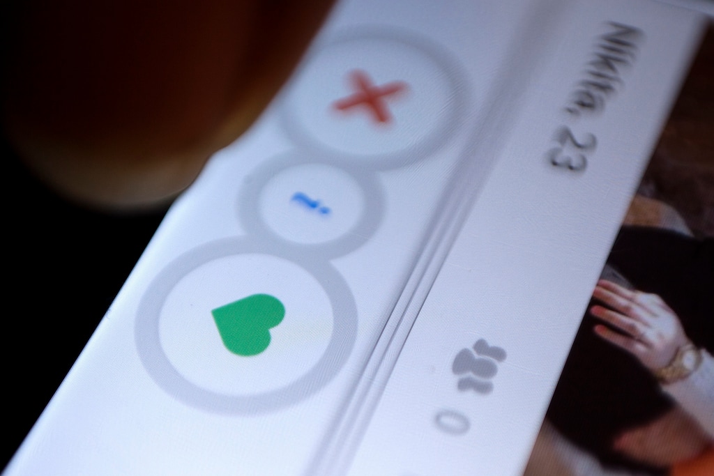 (Tsering Topgyal | The Associated Press) In this July 5, 2015, file photo, a man uses the dating app Tinder in New Delhi.