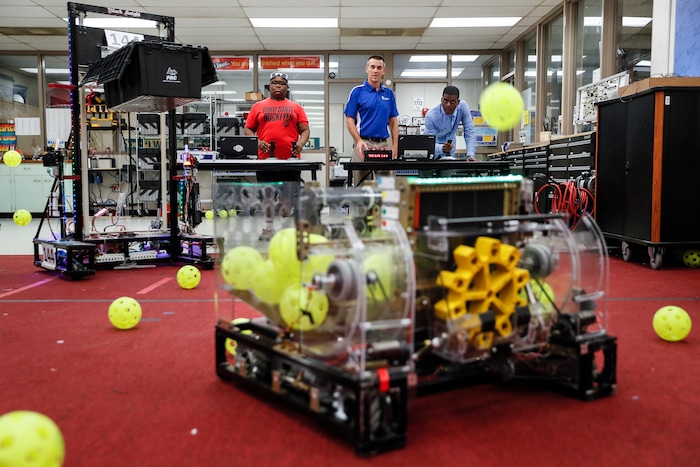 In this May 18, 2017 photo, engineering instructor David Campbell, center, assists his students as they operate a robot designed and built for competition by their fellow classmates at Colerain High School in Cincinnati. Campbell's team entered into the 2017 FIRST Robotics international high school robotics competition, serving as a showcase for local talent while encouraging students to pursue engineering, software development, and technology design fields. (AP Photo/John Minchillo)
