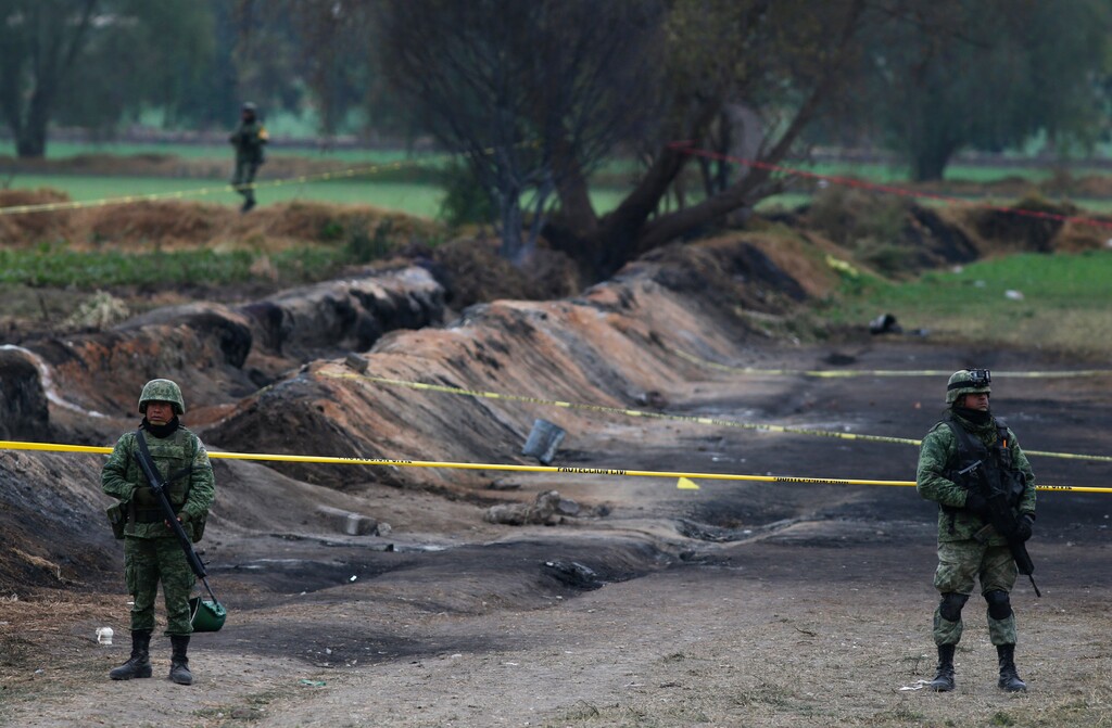Soldiers guard the site where a gas pipeline exploded two days prior, in the village of Tlahuelilpan, Mexico, Sunday Jan. 20, 2019. A massive fireball that engulfed locals scooping up fuel spilling from a pipeline ruptured by thieves in central Mexico killed dozens of people and badly burned dozens more on Jan. 18. (AP Photo/Claudio Cruz)