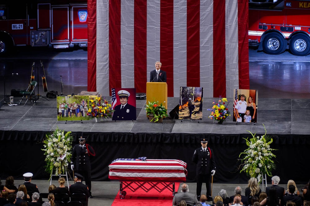 (Trent Nelson | The Salt Lake Tribune)  Speaking at his son Matthew Burchett's funeral, Tom Burchett smiles as voicemails left by Matthew are played. Funeral services for Battalion Chief Matthew Burchett at the Maverik Center in West Valley City, Monday Aug. 20, 2018.