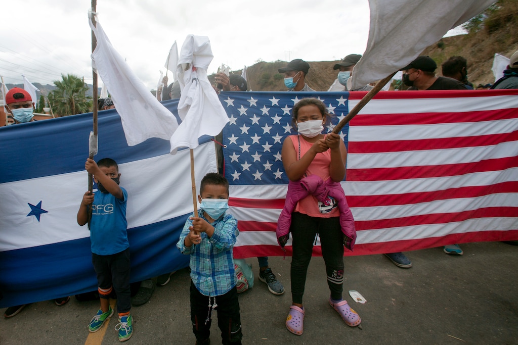 (Sandra Sebastian | AP photo)

Honduran migrant children raise white flags in front of a Honduran and American flag, as they are blocked by Guatemalan soldiers and police from advancing toward the U.S.-Mexico border, on the highway in Vado Hondo, Guatemala, Monday, Jan. 18, 2021. Some migrants have expressed hope about a friendlier reception from the new U.S. administration.
