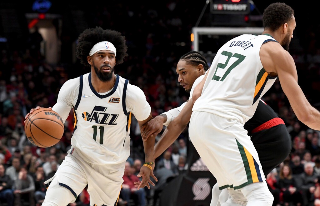 Utah Jazz guard Mike Conley, left, dribbles around a pick set by center Rudy Gobert, right, as Portland Trail Blazers guard Keon Johnson, center defends during the second half of an NBA basketball game in Portland, Ore., Sunday, April 10, 2022. The Jazz won 111-80. (AP Photo/Steve Dykes)