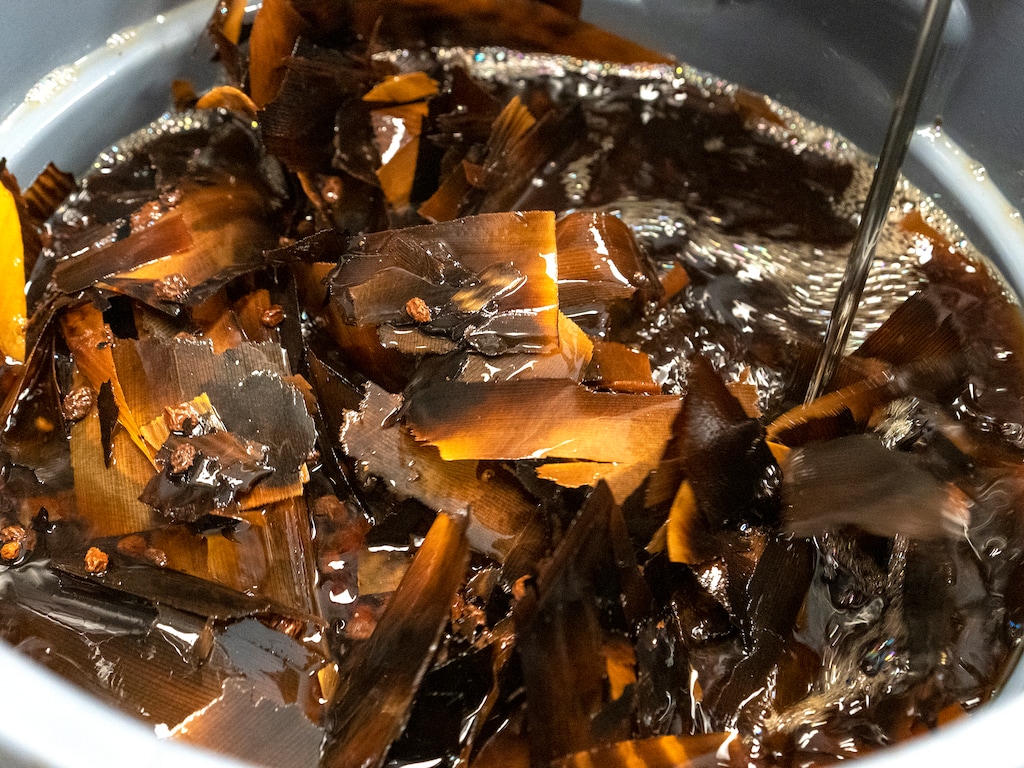 (Leah Hogsten | The Salt Lake Tribune) Abram Kimball stirs a vat of charred cedar and currant bitters, made with cedar bark shavings, in the kitchen at Bitters Lab, Tuesday, June 7, 2022. One batch of flavored bitters takes 30 days to make.