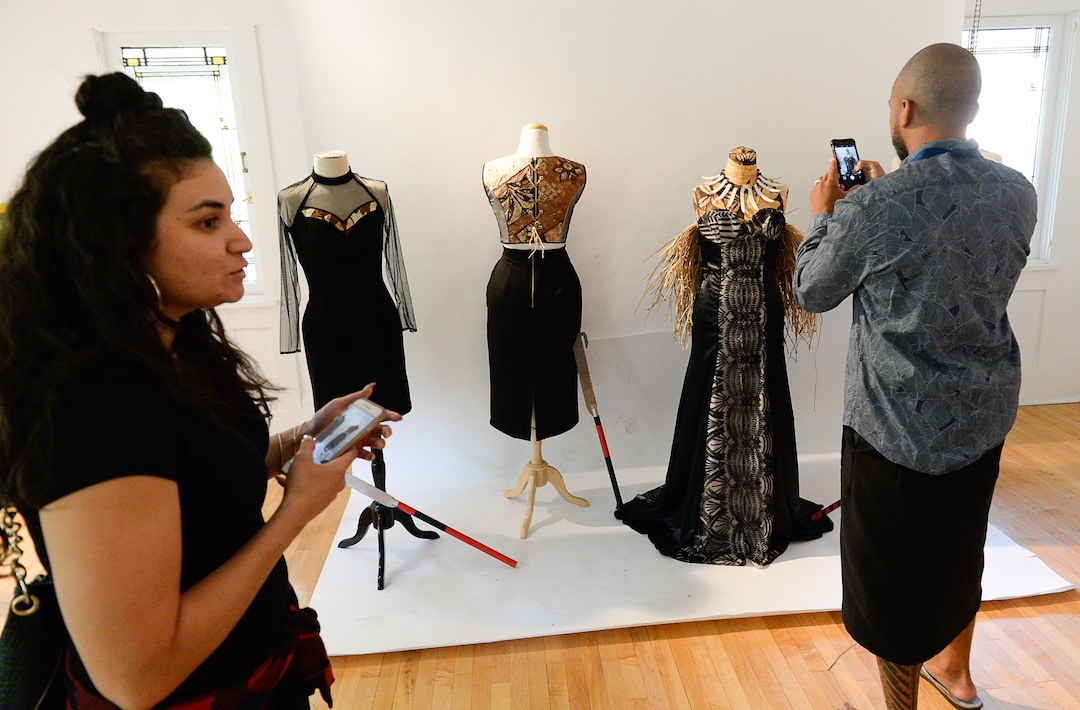 (Francisco Kjolseth  |  The Salt Lake Tribune)  Sina Thomsen, left, overlooks the dresses she made with tree bark as Lanakila Bush takes a picture of his traditional Samoan knives used in dance. The Pasifika Enriching Arts of Utah presented their 6th annual art exhibit at the Clubhouse, 850 E. South Temple on Saturday, Aug. 25, 2018, as part of Utah Pacific Islander Heritage Month to preserve culture and heritage through all types of mediums and disciplines.