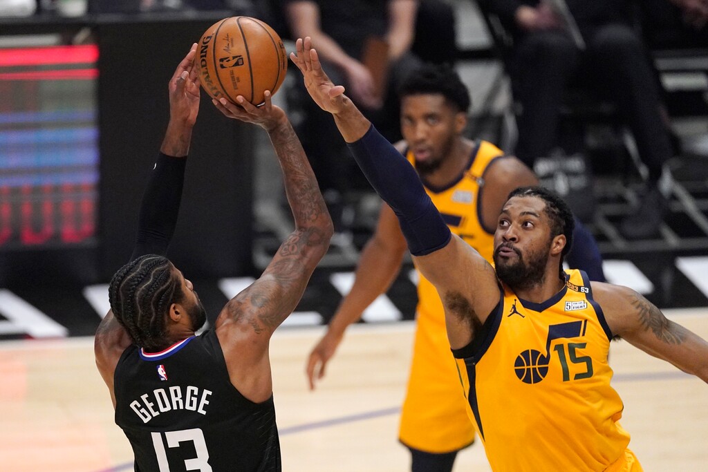 Los Angeles Clippers guard Paul George, left, shoots as Utah Jazz center Derrick Favors defends during the first half in Game 4 of a second-round NBA basketball playoff series Monday, June 14, 2021, in Los Angeles. (AP Photo/Mark J. Terrill)