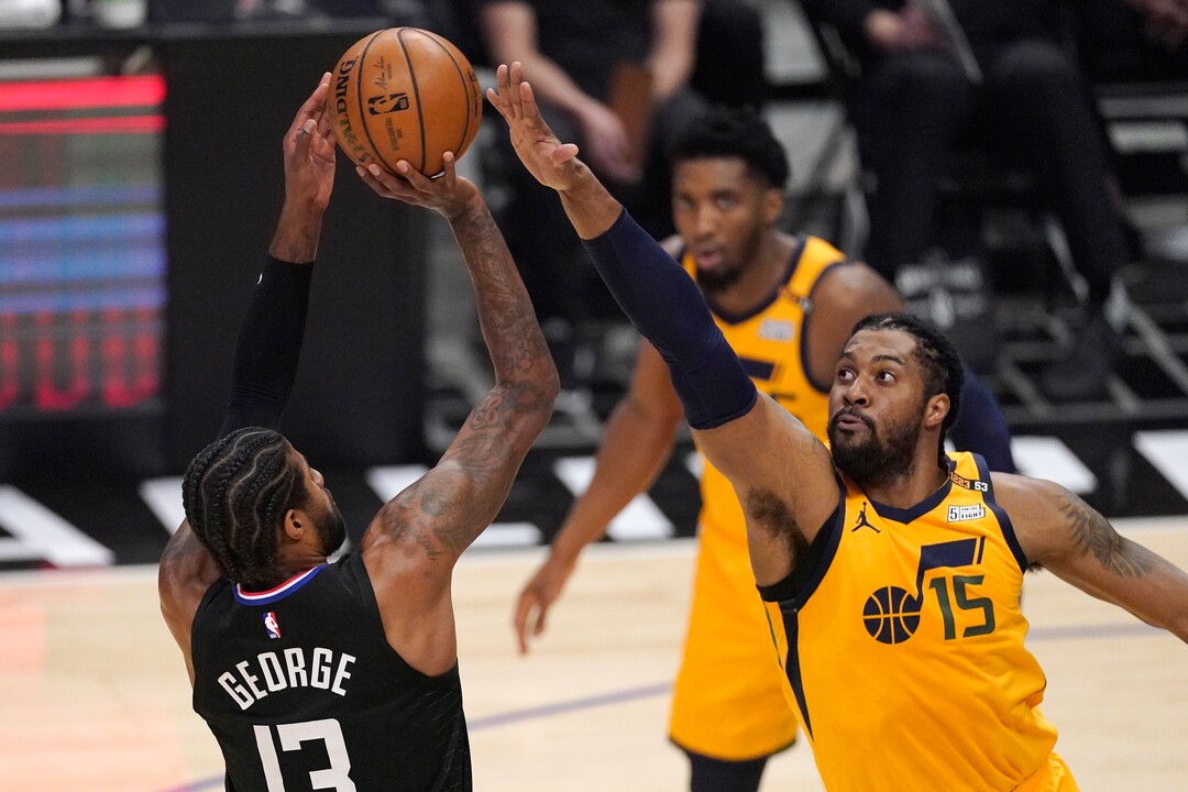 Los Angeles Clippers guard Paul George, left, shoots as Utah Jazz center Derrick Favors defends during the first half in Game 4 of a second-round NBA basketball playoff series Monday, June 14, 2021, in Los Angeles. (AP Photo/Mark J. Terrill)