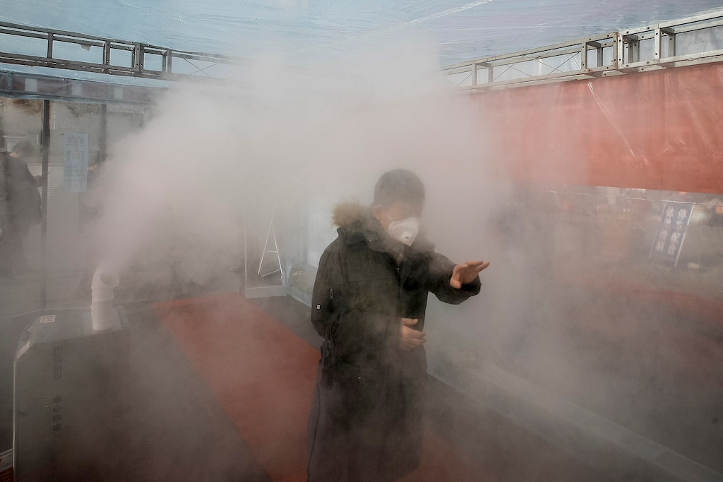 (Chinatopix Via AP) A man walks through a disinfectant spray in order to return home at a residential complex in northern China's Tianjin Municipality Tuesday, Feb. 11, 2020. China's daily death toll from a new virus topped 100 for the first time and pushed the total past 1,000 dead, authorities said Tuesday after leader Xi Jinping visited a health center to rally public morale amid little sign the contagion is abating.