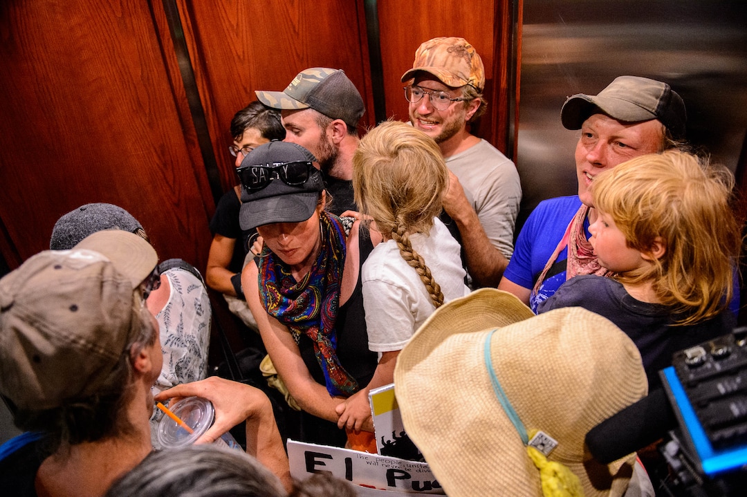 (Trent Nelson  |  The Salt Lake Tribune) Protesters ride an elevator up to the Chamber of Commerce office in Salt Lake City on Tuesday, July 9, 2019. Dozens of people showed up to protest the proposed Inland Port and ended up clashing with police, resulting in temporary street closures and arrests.