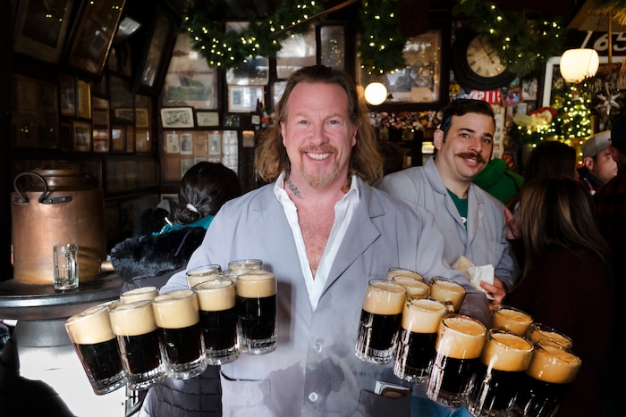 In this Dec. 27, 2019 photo, Gregory de la Haba serves 20 mugs of beer for a table of customers in McSorley's Old Ale House in New York. Located in Manhattan's Lower East Side, McSorley's opened in the mid-19th century and remained open as a speakeasy during Prohibition. The Prohibition Era, which lasted from Jan. 17, 1920, until December 1933, is now viewed in popular culture as a failed experiment that glamorized pervasive illegal drinking. (AP Photo/Mark Lennihan)