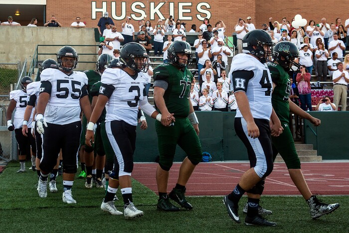 (Chris Detrick  |  The Salt Lake Tribune)    Members of the Hillcrest and Highland football teams hold hands as they walk onto the field before the game at Hillcrest High School Friday, September 1, 2017. Cazzie Brown passed away Sunday night after spending four days in the hospital. According to a family representative, Brown was brought to the emergency room Wednesday for complications with his thyroid. The doctors found that he had contracted meningitis, and later received a preliminary positive after being tested for West Nile virus. 