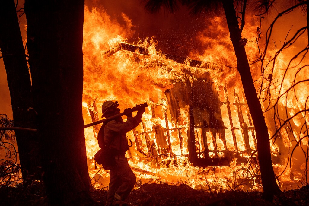 (Noah Berger | The Associated Press file photo) On Nov. 9, firefighter Jose Corona sprays water as flames from the Camp Fire consume a home in Magalia, Calif. A massive new federal report warns that extreme weather disasters, like California’s wildfires and 2018’s hurricanes, are worsening in the United States. The White House report quietly issued Friday, Nov. 23, also frequently contradicts President Donald Trump.