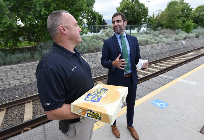 (Francisco Kjolseth | The Salt Lake Tribune) In honor of National Donut Day, Sandy Mayor Kurt Bradburn, right, teams up with interim Sandy Police Chief Bill O'Neal to hand out donuts to commuters on Friday, June 1, 2018, at the Sandy Civic Center TRAX Station. Bradburn is quoted as saying ÒI am excited to team up with the Sandy Police department on National Donut Day. Everyone knows how much police officers love donuts and we thought this would be a fun way to do something nice for our community. ItÕs really important to create positive interactions for residents with the police officers who serve our city and whatÕs more positive than free donuts? It is also a priority of mine, as Mayor, to be out in the community so residents know me personally and feel connected to their city government.Ó