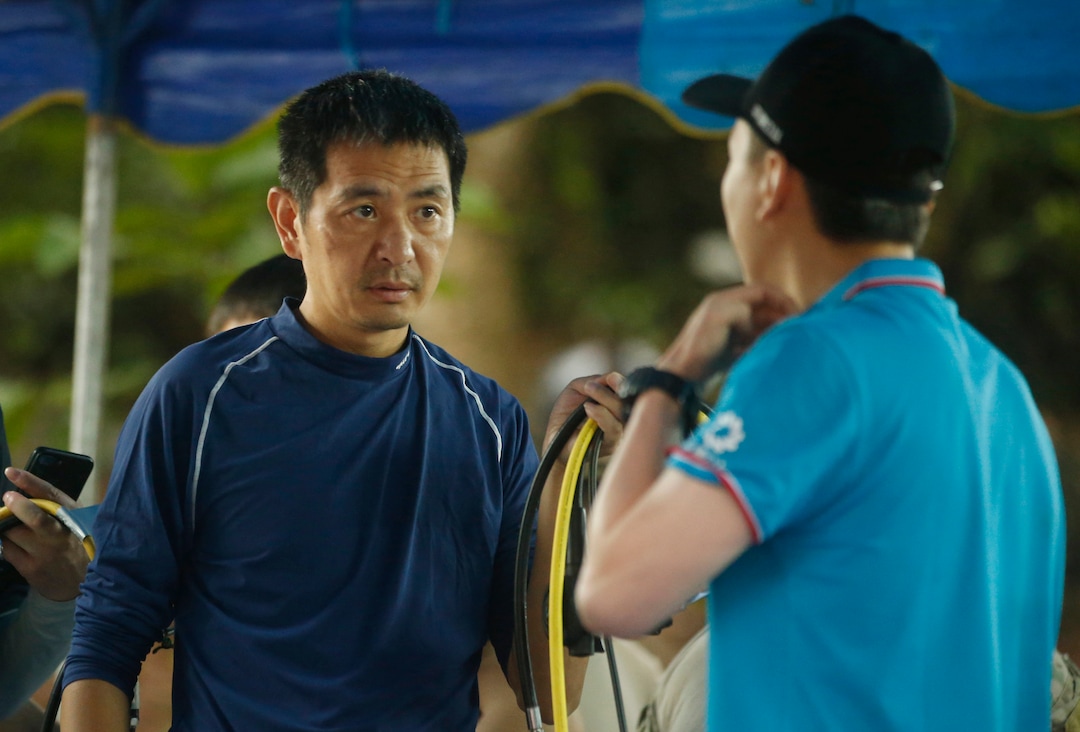 Chinese rescues team members talk near a cave complex where 12 boys and their soccer coach went missing, in Mae Sai, Chiang Rai province, in northern Thailand, Monday, July 2, 2018. Rescue divers are advancing in the main passageway inside the flooded cave in northern Thailand where the boys and their coach have been missing more than a week. (AP photo/Sakchai Lalit)