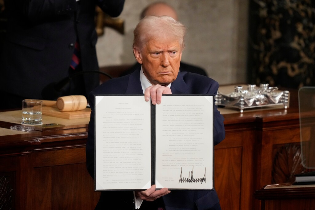 President Donald Trump holds up a signed executive order as he addresses a joint session of Congress at the Capitol in Washington, Tuesday, March 4, 2025. (AP Photo/Alex Brandon)