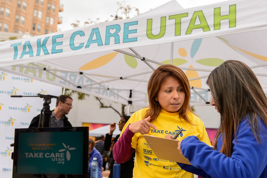 (Trent Nelson | The Salt Lake Tribune) Julie Contreras, one of Take Care Utah’s team of enrollment assisters, offers help and advice about applying for health insurance with attendees at the Hispanic Heritage Parade in Salt Lake City, Saturday September 23, 2017.