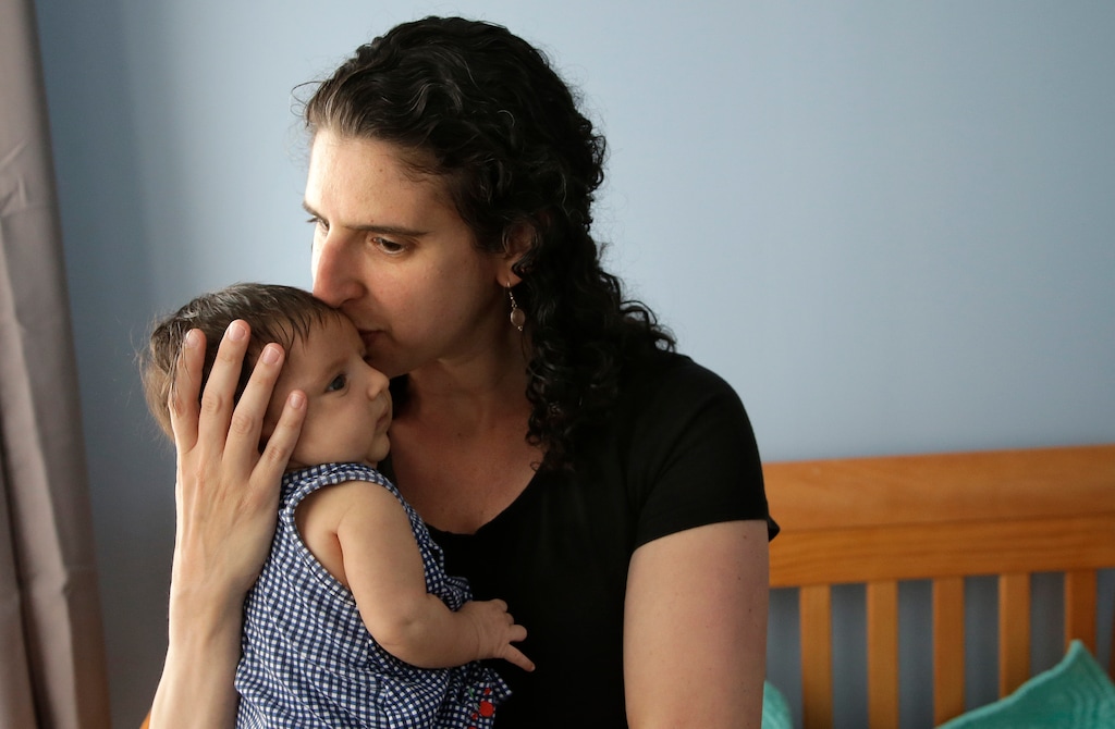 In this Thursday, June 1, 2017 photo Elena Tenenbaum kisses her eight-week-old baby Zoe while standing for a photograph at their home in Providence, R.I. Tenenbaum, a clinical psychology researcher, had her second daughter in April of 2017, and has been able to use Rhode Island's paid family leave program, which started in 2014 and covers four weeks of partial pay. (AP Photo/Steven Senne)