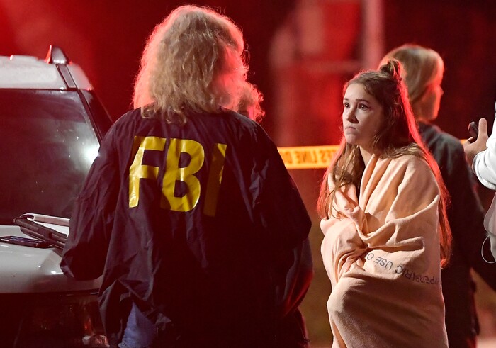An FBI agent talks to a potential witness as they stand near the scene Thursday, Nov. 8, 2018, in Thousand Oaks, Calif. where a gunman opened fire Wednesday inside a country dance bar crowded with hundreds of people on "college night," wounding 11 people including a deputy who rushed to the scene. Ventura County sheriff's spokesman says gunman is dead inside the bar. (AP Photo/Mark J. Terrill)