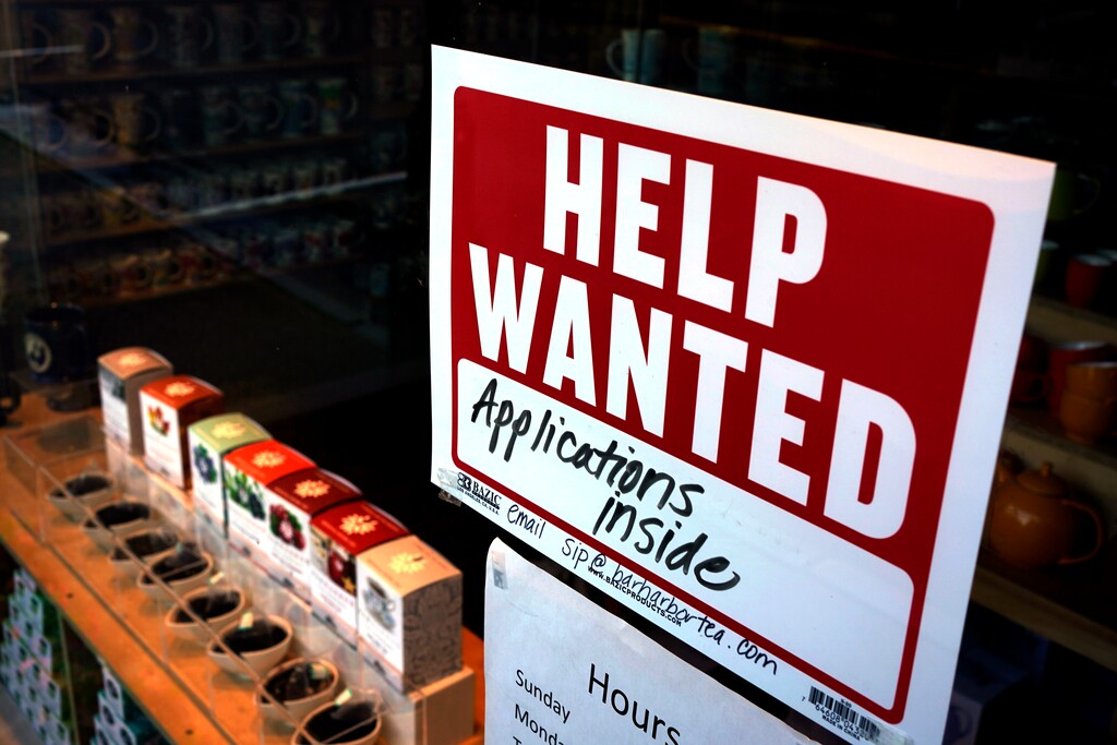 A help-wanted sign hangs in the front window of the Bar Harbor Tea Room on Saturday, June 11, 2022, in Bar Harbor, Maine. America’s employers shrugged off high inflation and weakening growth to add 372,000 jobs in June, a surprisingly strong gain that will likely spur the Federal Reserve to keep sharply raising interest rates to try to cool the economy and slow price increases. (Robert F. Bukaty via AP)