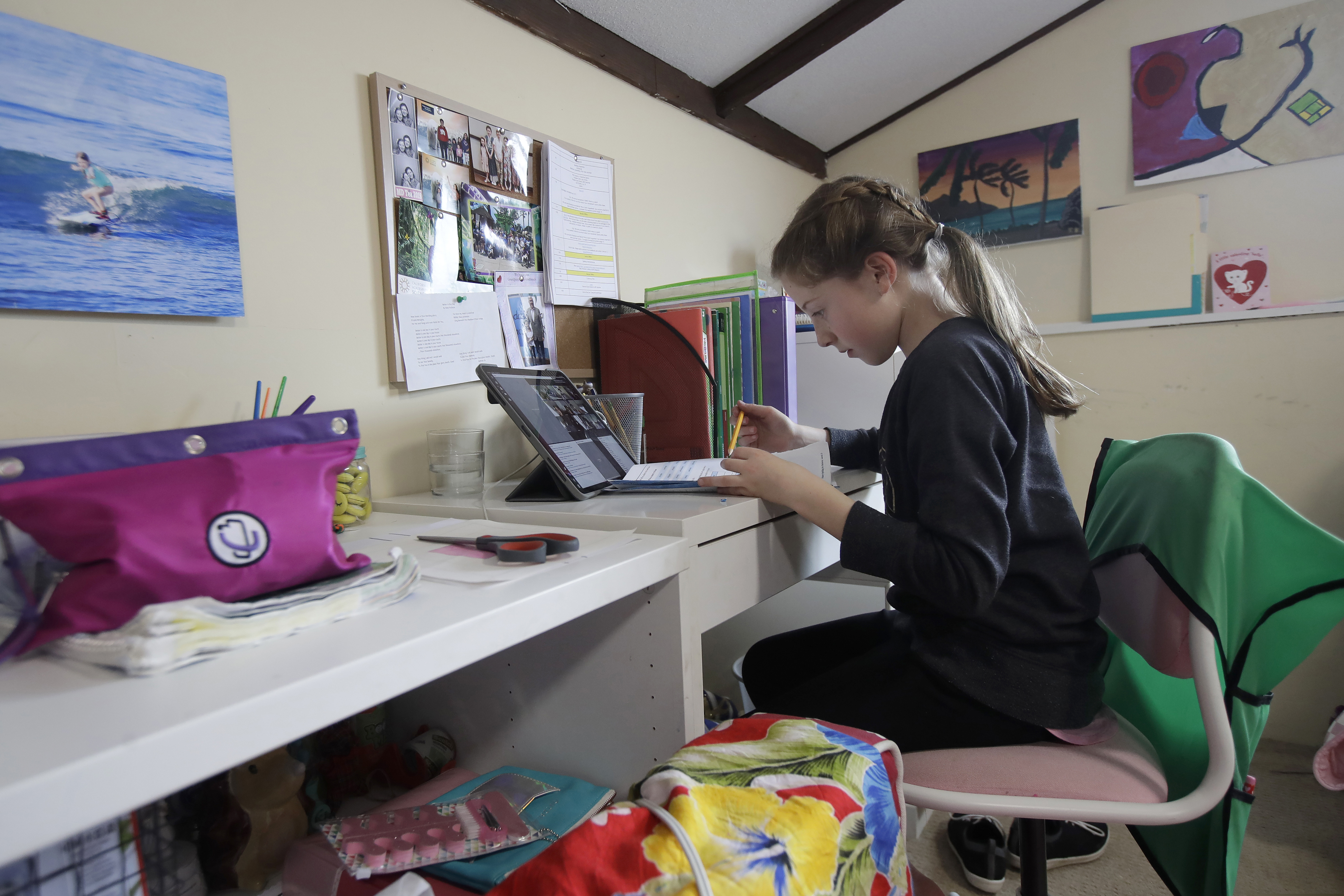 FILE - In this March 19, 2020 file photo, Rachel Keenan takes a live class online at her home in San Francisco. When students return to school after a lengthy pandemic-induced absence, the consensus is they will have lost significant academic ground. Still unresolved for governments and educators are the questions of how — or even whether — teachers should try to make up for lost learning. (AP Photo/Jeff Chiu, File)