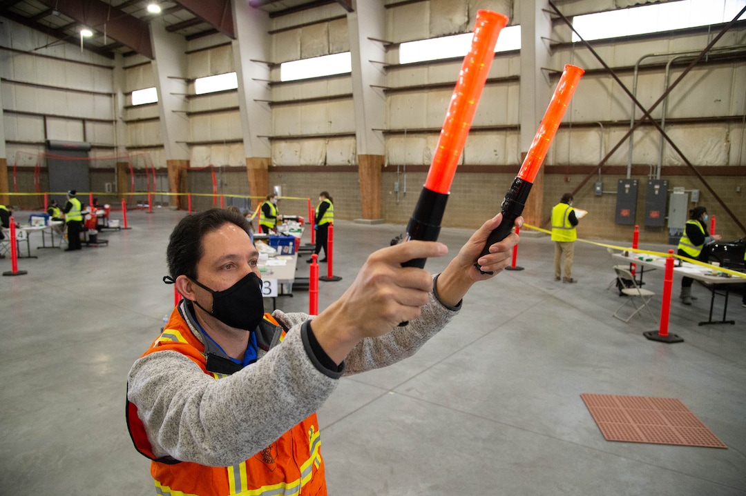 (Francisco Kjolseth  | The Salt Lake Tribune) Robert Nunn with Davis County Environmental Services, lends a hand directing traffic as the Davis County School District begins COVID-19 vaccinations for its teachers at the Davis County Legacy Center in Farmington on Tuesday, Jan. 12, 2021.