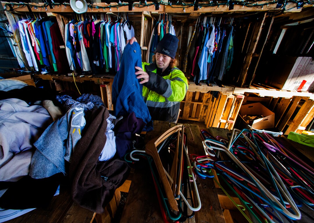 (Rick Egan | The Salt Lake Tribune) Brandy DeGarmo, wears a reflective green jacket, as the manager of the clothing area, as she sorts through donations to hang on the clothes rack made of shipping pallets, at Camp Last Hope, on Tuesday, Jan. 5, 2021.