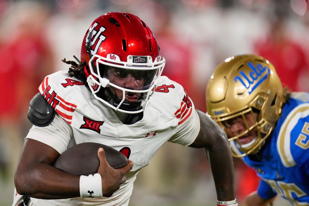 Utah quarterback Devon Dampier, left, runs the ball as UCLA defensive lineman A.J. Fuimaono gives chase during the first half of an NCAA college football game, Saturday, Aug. 30, 2025, in Pasadena, Calif. (AP Photo/Mark J. Terrill)