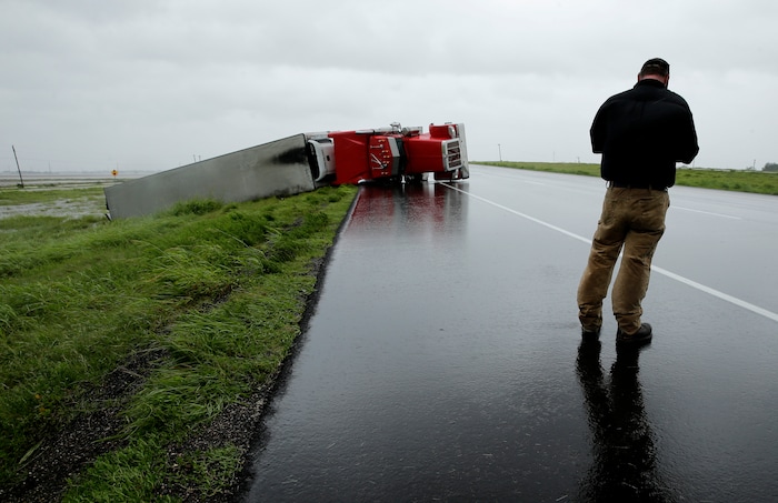 (Charlie Riedel  |  AP Photo) A passing motorist stops to look at a flipped truck in the aftermath of Hurricane Harvey Saturday, Aug. 26, 2017, north of Victoria, Texas.