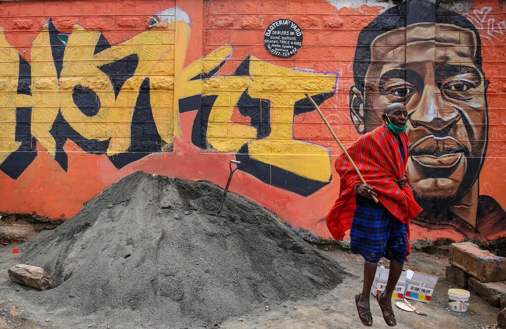 (Brian Inganga | AP photo)
In this June 3 photo, a Maasai man, who said he had seen Facebook video about protests in the U.S. over the death of George Floyd, jumps next to a new mural painted showing Floyd with the Swahili word "Haki" meaning "Justice", in the Kibera slum, or informal settlement, of Nairobi, Kenya. Since George Floyd's death in the U.S. state of Minnesota last week, his face has been painted on walls from Nairobi, Kenya to Idlib, Syria. Floyd's name has been inked on the shirts of soccer players and chanted by crowds from London and Cape Town to Tel Aviv and Sydney.