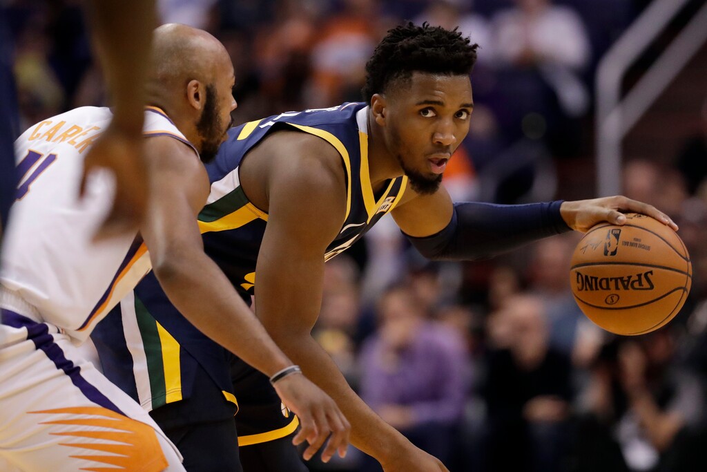 Utah Jazz guard Donovan Mitchell, right, looks to pass as Phoenix Suns guard Jevon Carter (4) defends during the first half of an NBA basketball game, Monday, Oct. 28, 2019, in Phoenix. (AP Photo/Matt York)