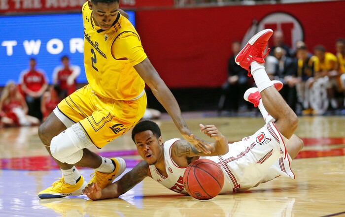 Utah guard Justin Bibbins (1) dives for a loose ball as California guard Juhwan Harris-Dyson (2) defends during the second half during an NCAA college basketball game Saturday, Feb. 10, 2018, in Salt Lake City. (AP Photo/Rick Bowmer)