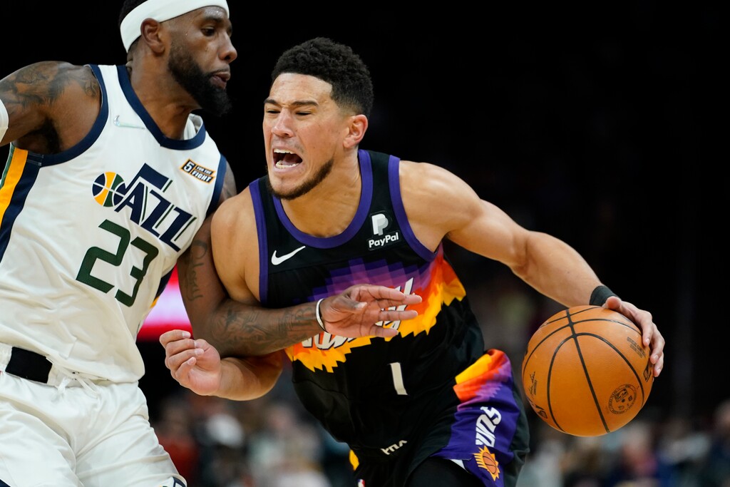 Phoenix Suns guard Devin Booker (1) drives as Utah Jazz forward Royce O'Neale (23) defends during the second half of an NBA basketball game, Sunday, Feb. 27, 2022, in Phoenix. The Jazz defeated the Suns 118-114. (AP Photo/Matt York)