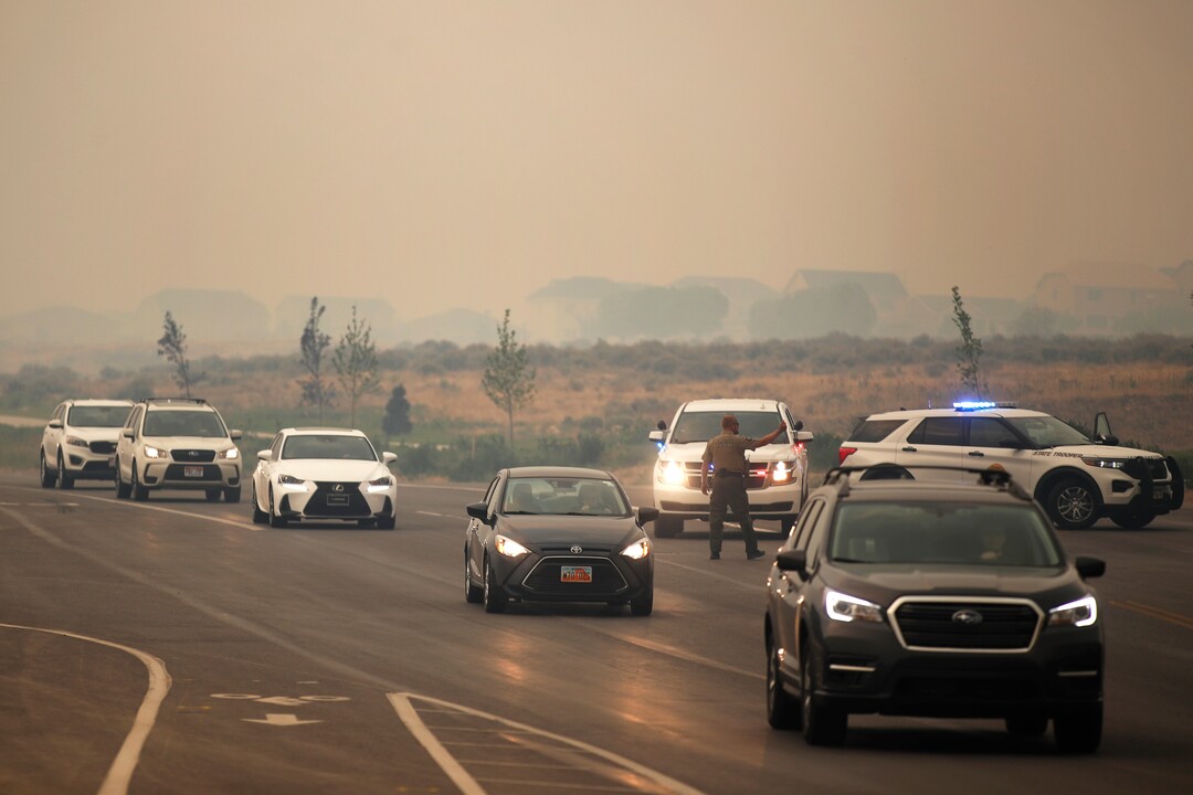 (George Frey  |  for The Salt Lake Tribune) An officer directs traffic as people are evacuated from their homes in south Saratoga Springs due to a wildfire on June 28, 2020.