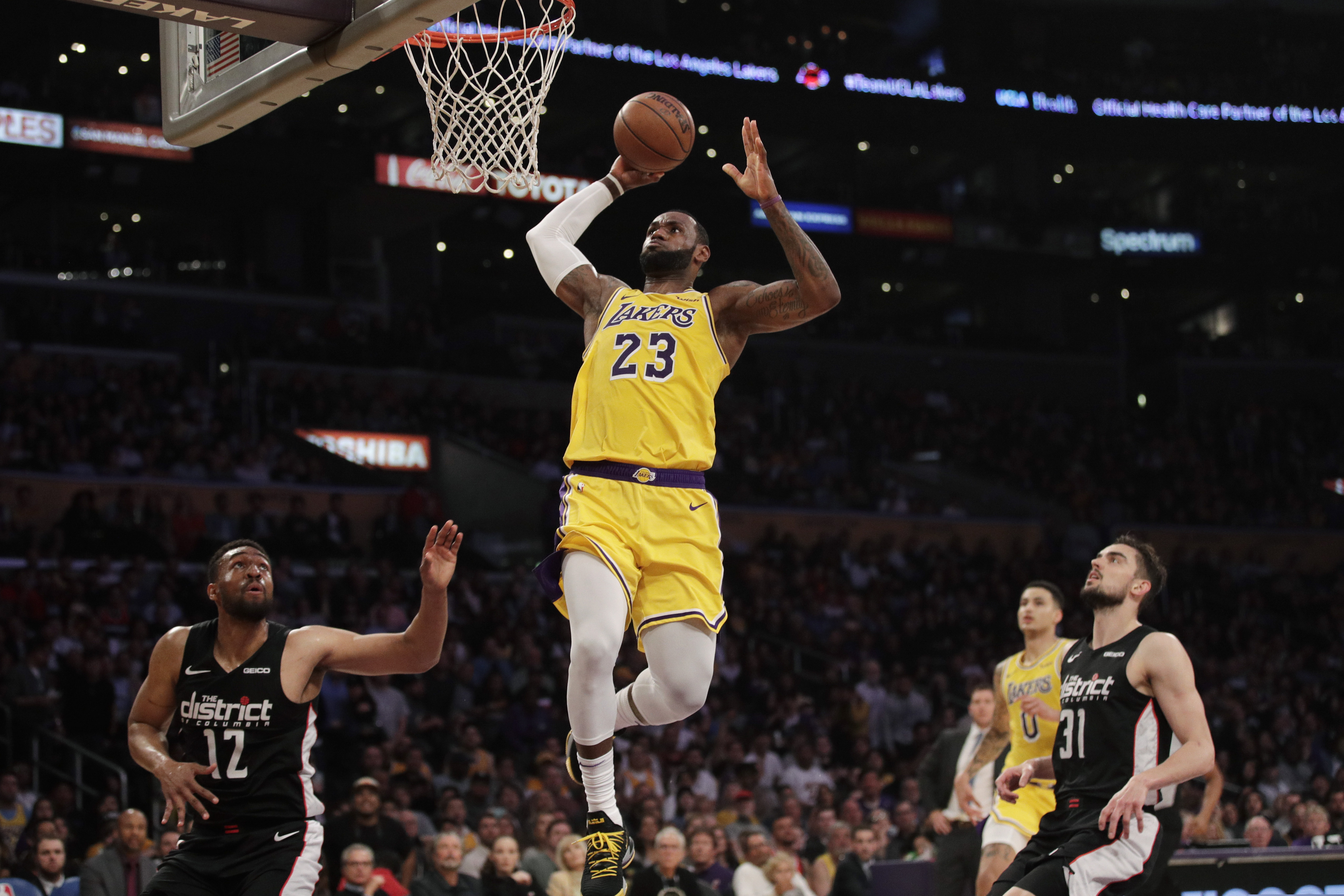 Los Angeles Lakers' LeBron James, center, goes up for a dunk as Washington Wizards' Jabari Parker, bottom left, and Tomas Satoransky look on during the first half of an NBA basketball game, Tuesday, March 26, 2019, in Los Angeles. (AP Photo/Jae C. Hong)