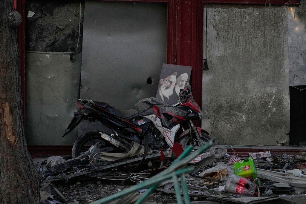(Vahid Salemi | AP) A poster of the late Supreme Leader Ayatollah Ali Khamenei, who was killed during the ongoing joint U.S.-Israeli military campaign, and the late Iranian Revolutionary founder Ayatollah Khomeini, right, lays on a motorcycle amid debris left by a strike in Tehran, Iran, Monday, March 2, 2026.