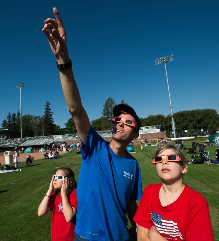  (Rick Egan  |  The Salt Lake Tribune)  Marc Nordby,  Anastazia, 12, Isadora, 10, of Coeur d'Alene, ID, watch the early stages of the solar eclipse at Melaleuca Baseball Park, in Idaho Falls, Monday, August 21, 2017.


