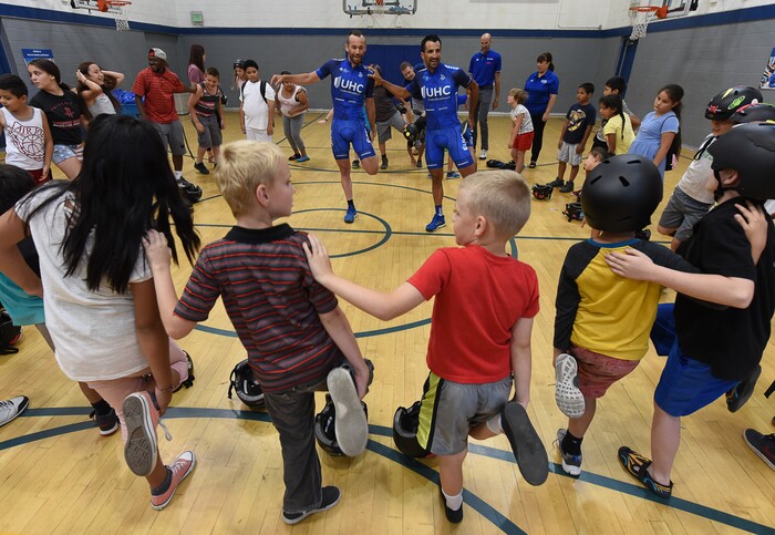 (Francisco Kjolseth | The Salt Lake Tribune) In advance to the upcoming Tour of Utah bicycle race, more than 50 Salt Lake City-area kids receive a new bicycle helmet at the Capitol West Boys & Girls Club on Tuesday, July 31, 2018. As part of UnitedHealthcare's Pro Cycling team and community outreach program to keep kids healthy and active, team cyclists Jonny Clarke, left, and Sebastian Haedo engage the kids in a few warm up routines before getting on the bike.