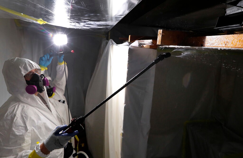 In this Oct. 18, 2017, photo, Asbestos Removal Technologies Inc., job superintendent Ryan Laitila, left, sprays amended water as job forman Megan Eberhart holds a light during asbestos abatement in Howell, Mich. Spurred by the chemical industry, President Donald Trump’s administration is retreating from a congressionally mandated review of some of the most dangerous chemicals in public use. The review began under Trump’s predecessor to make sure proper safeguards are in place for asbestos and other toxins in homes, offices and industrial plants across the United States. (AP Photo/Paul Sancya)