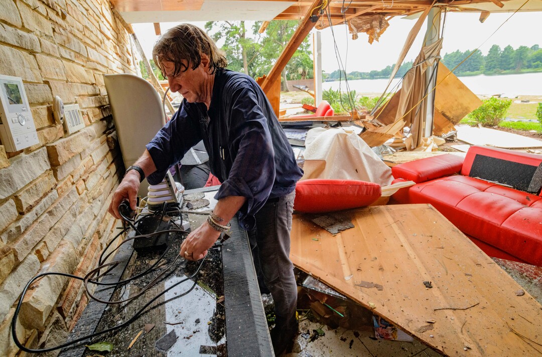(Matthew Hinton | AP Photo) Eric Ehlenberger, a physician and neon artist, goes through his damaged home in New Orleans on Wednesday, July 10, 2019, following a storm that swamped the city and paralyzed traffic. Ehlenberger said his wife was able to crawl out safely.