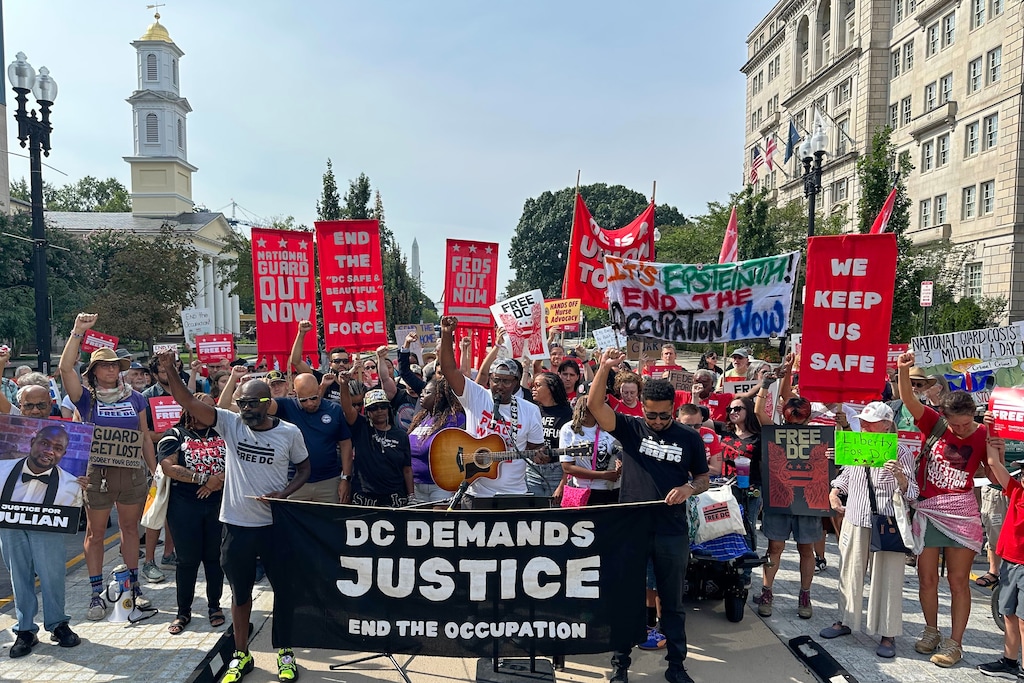 Near the White House, protesters from Free DC rally against continued National Guard presence in the district, on the one year anniversary of President Trump's emergency declaration activating the National Guard, Tuesday, Aug. 11, 2026, in Washington. (AP Photo/Nathan Ellgren)